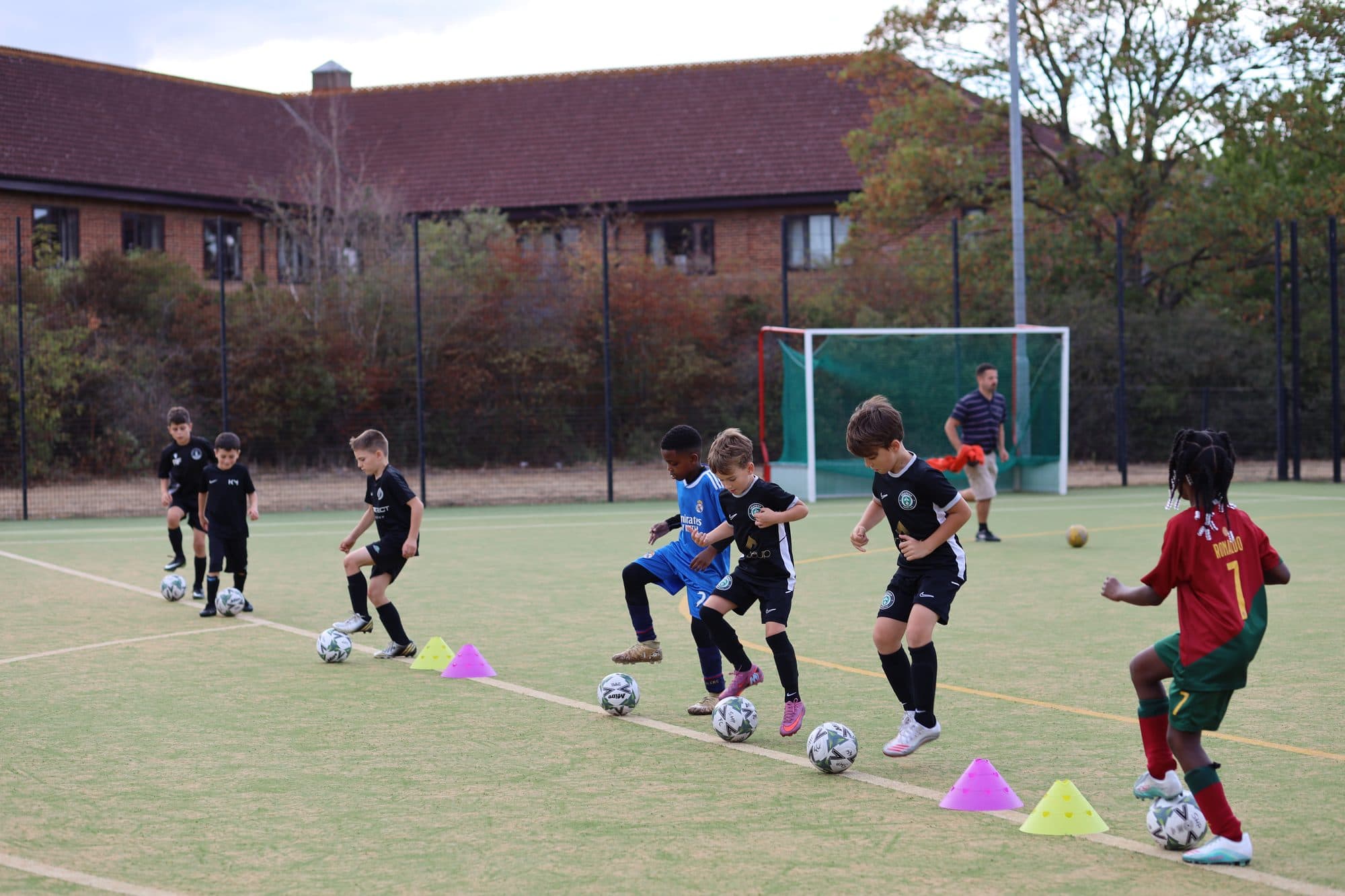 Young players practise close ball control in a line, each with a ball at their feet