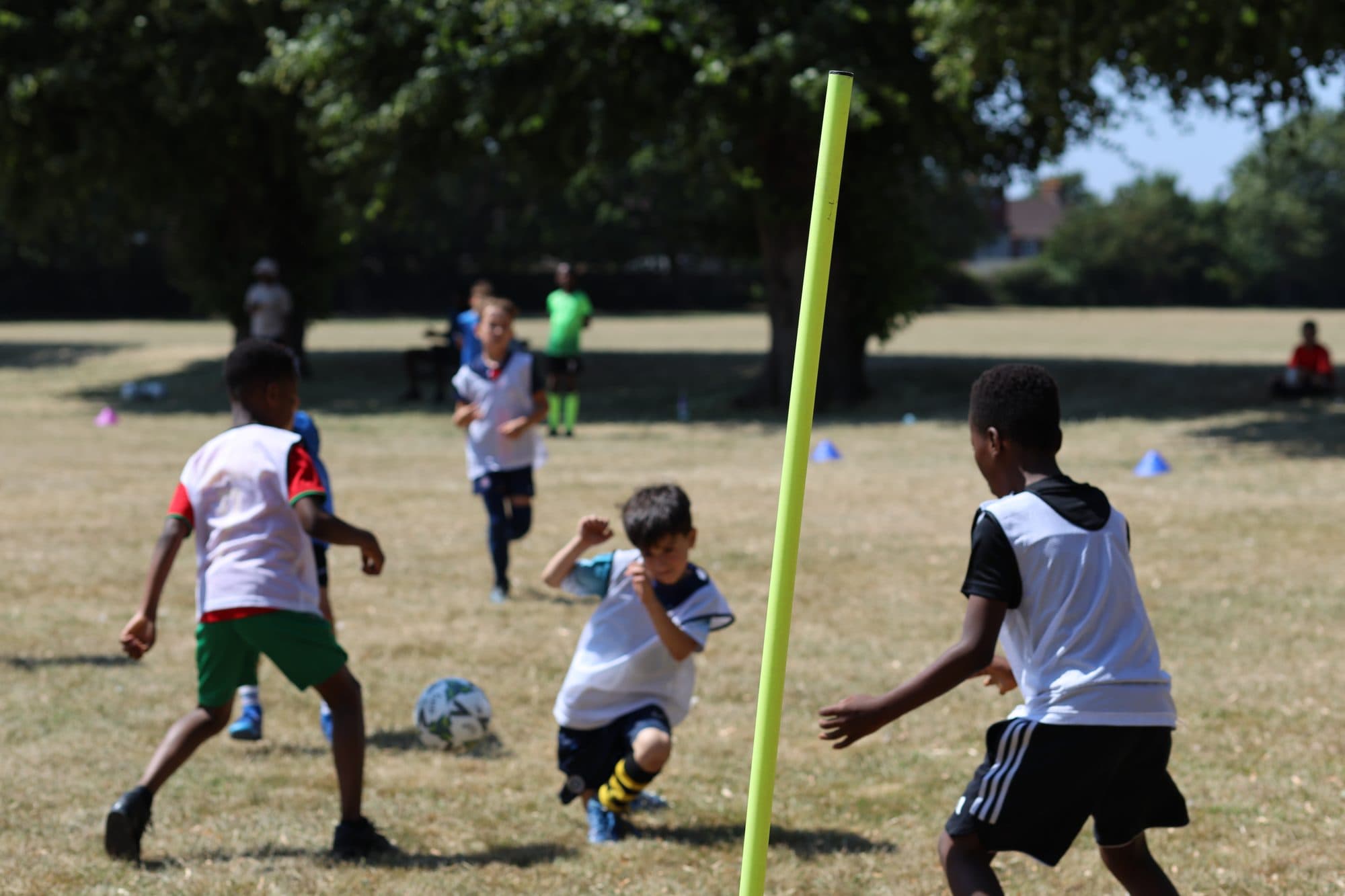 A young player twists past opponents next to a yellow training pole