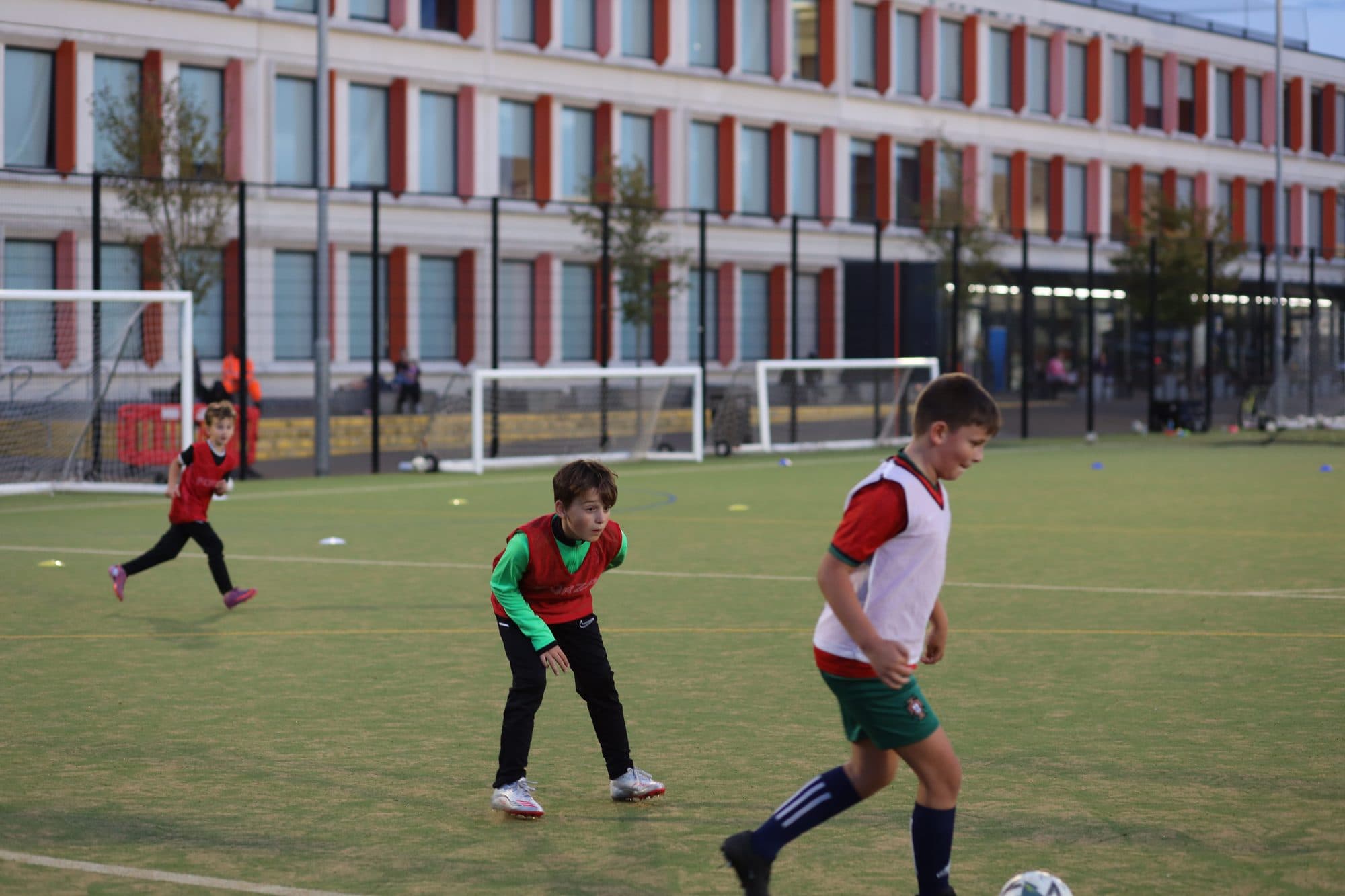 A player in a white bib drives forward with the ball as others close in