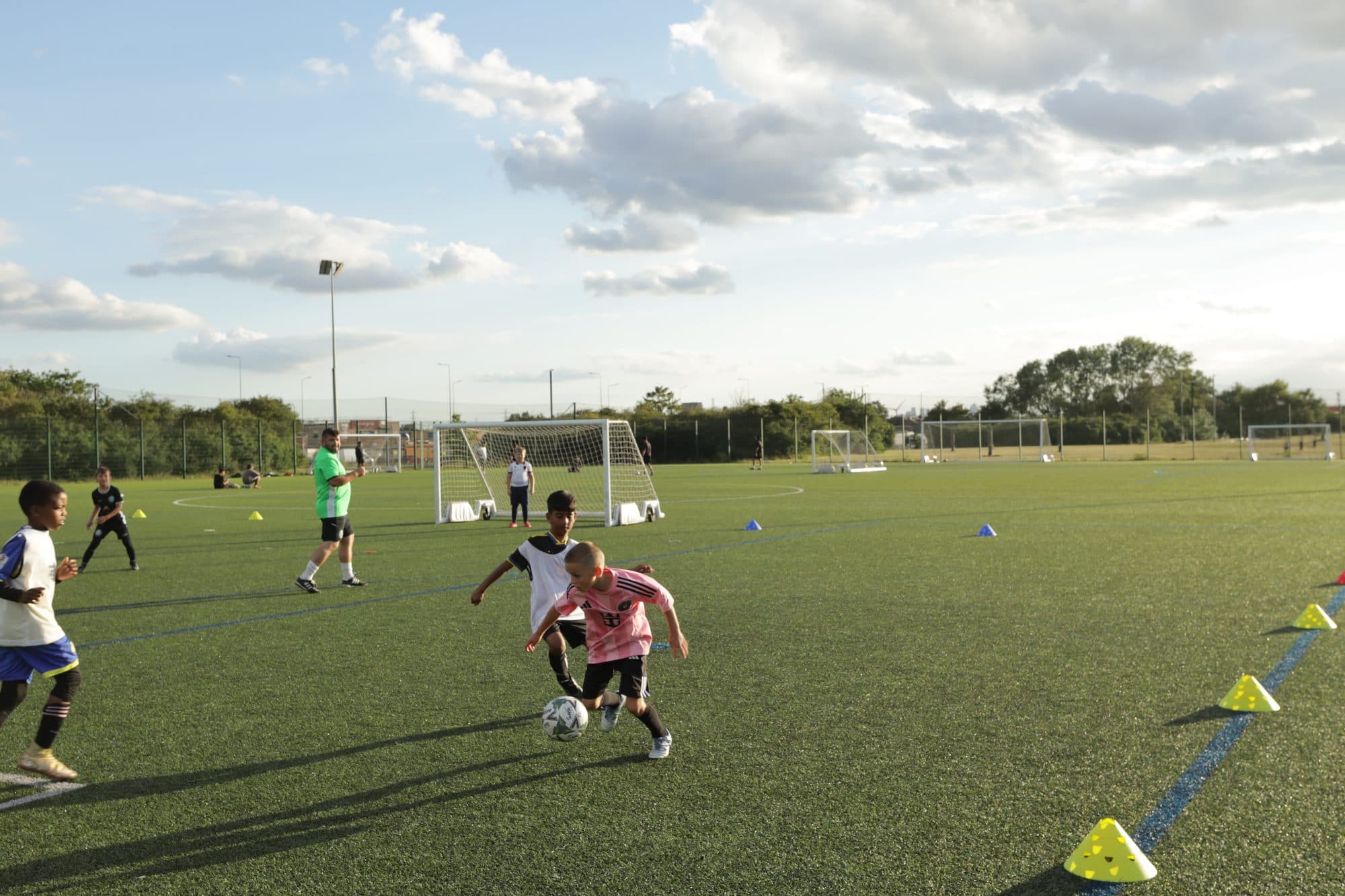 A player in pink dribbles past a defender in the evening sun