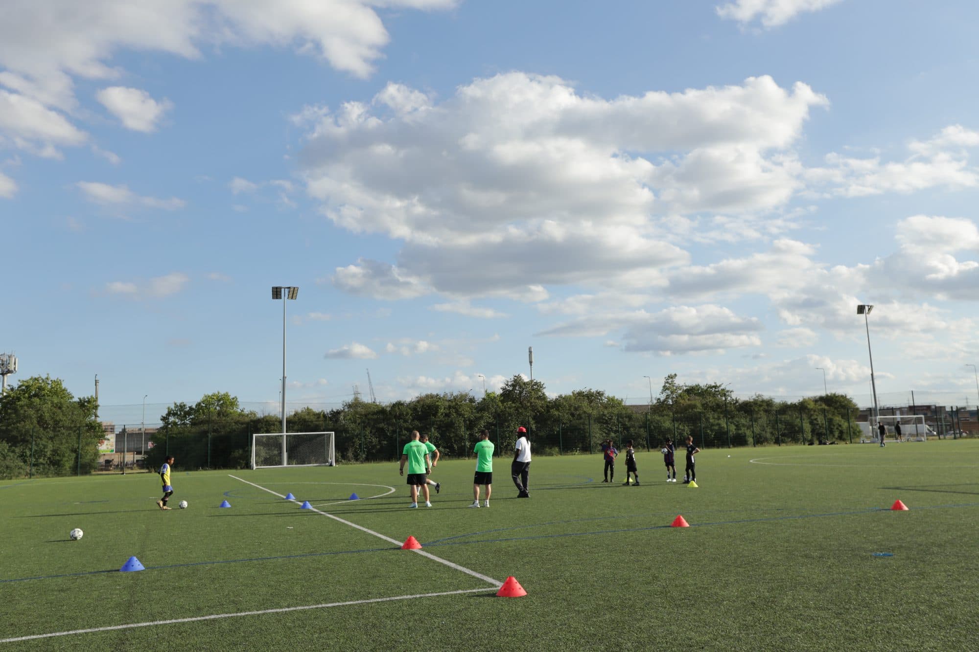 A session on a large artificial pitch under a wide sky with white clouds