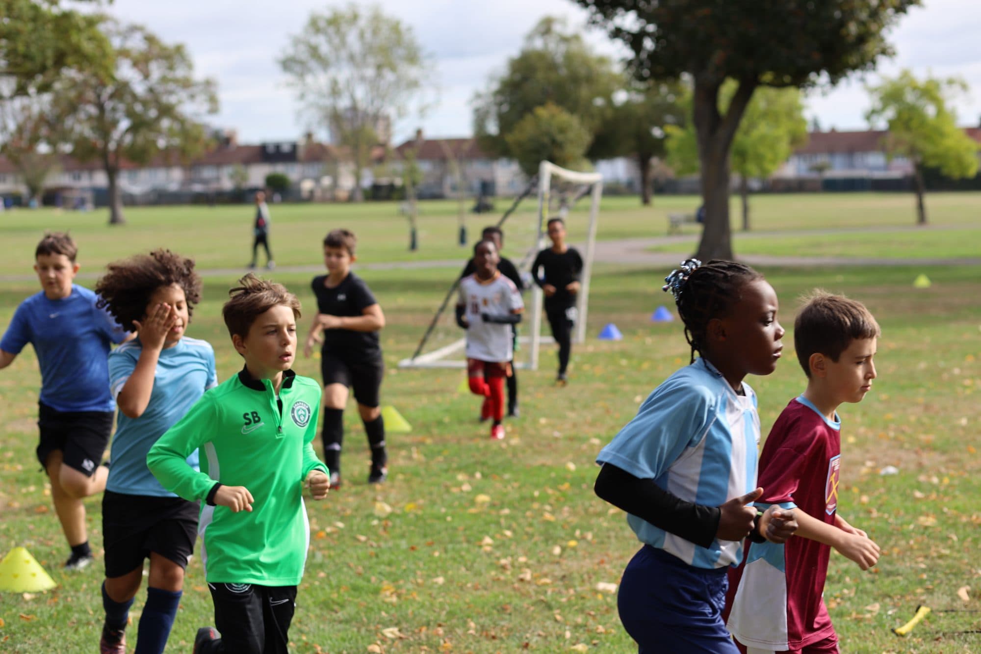Young players run with smiles across the grass during an autumn session in the park